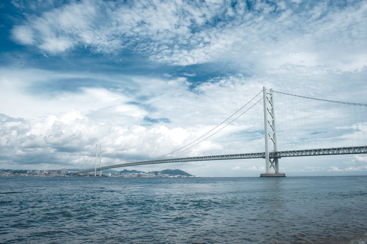 Stunning view of Akashi-Kaikyo Bridge in Awaji, Hyogo, Japan against a vibrant blue sky.